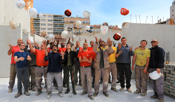 Collaborateurs sur chantier jetant leurs casques en l’air